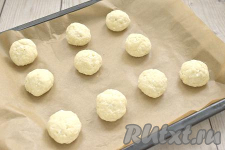 Противень застилаем пергаментом. Смачивая руки водой, из каждого кусочка творожного теста скатываем шарик и выкладываем на застеленный противень. Между шариками обязательно оставляем место, ведь в процессе выпечки пончики увеличатся в объёме. Я использовала силиконизированный пергамент, к нему тесто не пристаёт в процессе выпечки. Если не уверены в качестве пергамента, который вы используете, тогда вначале слегка смажьте его растительным маслом, а уже затем выкладывайте заготовки творожных пончиков.