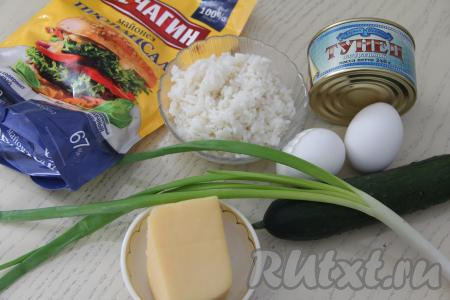 Подготовить продукты для приготовления салата с консервированным тунцом, рисом, яйцом и огурцом. Рис промыть водой, выложить в кастрюлю с уже закипевшей подсоленной водой и варить с момента закипания минут 20 (до готовности, то есть рисинки должны стать мягкими, но не переваренными), а затем откинуть на дуршлаг, чтобы убрать лишнюю воду). Отварить яйца в течение 10 минут после начала кипения воды, дать им остыть, очистить. Вымыть огурец и зелёный лук.