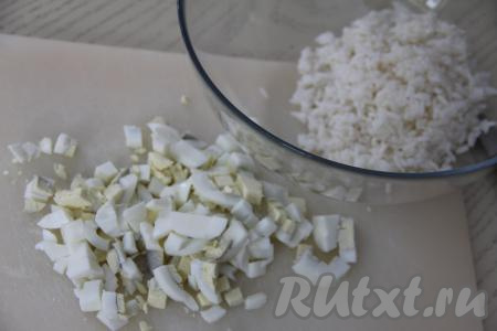 В салатник выложить рис. Яйца мелко нарезать.