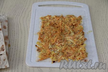 Выложить на доску первый лист лаваша, равномерно выложить на него половину овощной начинки.