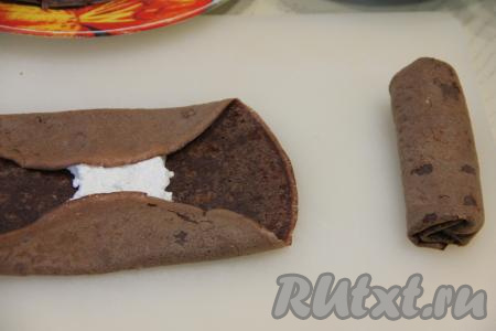 Подвернуть края каждого блина на начинку, а затем свернуть блинчик в трубочку.