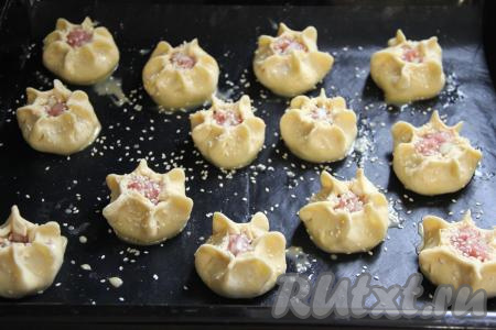 Яйцо взбить в небольшой ёмкости до однородности. Смазать пирожки взбитым яйцом и присыпать кунжутом. Поставить противень с пирожками с мясом в разогретую духовку и выпекать при температуре 180 градусов примерно 40 минут (до золотистости песочного теста).