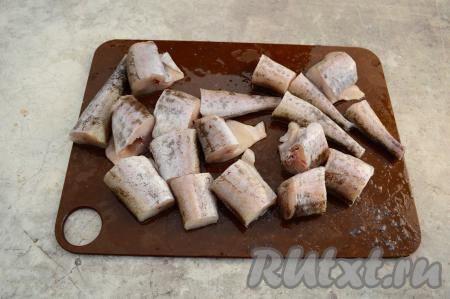 Тушки минтая поскоблить ножом, отрезать плавники, удалить внутренности и чёрную плёночку из брюшек рыб. Нарезать рыбу на порционные кусочки шириной примерно 4 сантиметра.