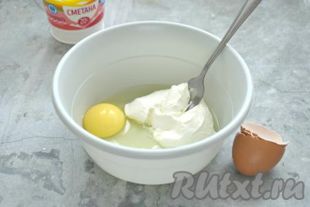 В миску выкладываем сметану и разбиваем к ней куриное яйцо, перемешиваем вилкой до однородности.