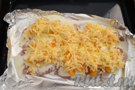 Поверх апельсина обильно присыпать куриное филе сыром, натёртым на крупной тёрке. Противень с подготовленными отбивными отправить в разогретую духовку.