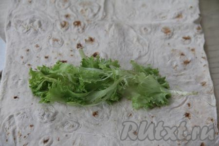 Вымыть листья салата, обсушить. ​​​​Лаваш разрезать на 2 части, соответственно мы будем готовить 2 шаурмы с тунцом. Ближе к одному краю лаваша выложить 3-4 листа салата.