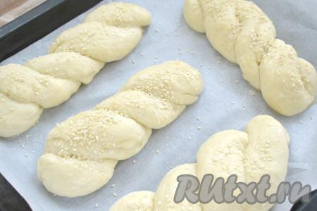 Аналогично формируем все 4 булочки. Выкладываем эти булочки на расстоянии друг от друга на противень, застеленный бумагой для выпечки. Прикрываем булочки полотенцем и оставляем минут на 30 для расстойки. Затем в небольшой ёмкости взбиваем вилкой сырое яйцо. Смазываем булочки взбитым яйцом, обильно посыпаем ванильным сахаром, немного присыпаем кунжутом и отправляем в духовку, прогретую до 180 градусов.