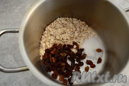 В кастрюлю с толстым дном всыпать овсяные хлопья, сахар и подготовленный изюм.