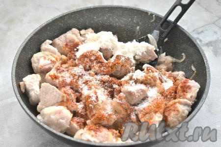 Обжаренное мясо по вкусу солим, перчим, добавляем молотую паприку, сушёный (или мелко нарезанный свежий) чеснок. Именно благодаря паприке гуляш из свинины приобретёт красивый цвет. Всыпаем муку, перемешиваем, продолжаем обжаривать мясо ещё 2 минуты.