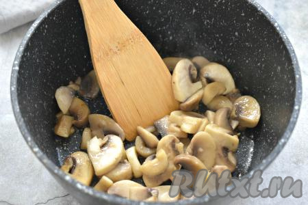 Разогреваем в сотейнике или на сковороде растительное масло, выкладываем нарезанные шампиньоны и обжариваем их 8-10 минут (до готовности и полного испарения жидкости), затем убираем с огня и даём остыть.