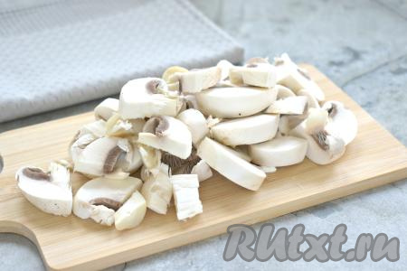 Прежде всего отварим куриное мясо, для этого кладём часть курицы в кастрюлю (у меня - куриный окорочок), заливаем полностью водой, ставим на огонь, а после закипания, убрав пену, солим и варим до готовности на небольшом огне (минут 30-35), затем достаём мясо и даём ему остыть. Свежие шампиньоны очищаем от загрязнений и ополаскиваем водой. Нарезаем грибы на средние кусочки.