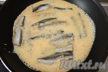 После того как мойва обжарится в течение 8 минут, влить в сковороду яйца.