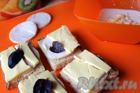 На 4 куска хлеба положите ломти сыра, затем ветчину (тут куриная) и снова ломти сыра, по желанию добавьте зелень.