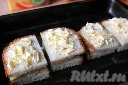 Накройте сверху каждый кусок с начинкой куском с маслом. Смешайте молоко с тёртым сыром и эту смесь разложите на сэндвичи. 