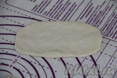 Разделить тесто на 12 равных частей. Каждую часть теста на слегка присыпанной мукой поверхности раскатать скалкой в овал, чуть больший по длине, чем длина сосиски. Толщина теста после раскатки примерно 2 миллиметра.