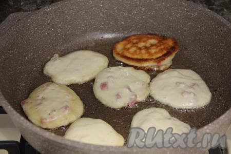 В сковороду влить растительное масло, очень хорошо его разогреть, уменьшить огонь до среднего. Выкладывать по 1 столовой ложке теста в виде круглых оладий. Жарить оладушки с сосисками с двух сторон до золотистого цвета, затем переложить на тарелку.