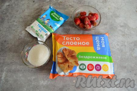 Подготовить продукты для приготовления слоек с творогом и клубникой. Заранее бездрожжевое (или дрожжевое) слоёное тесто достать из морозилки, чтобы оно разморозилось. Клубнику можно взять свежую или замороженную. Свежую клубнику нужно промыть водой, убирая чашелистики, затем обсушить. Замороженную клубнику слегка разморозить, слить лишнюю воду.