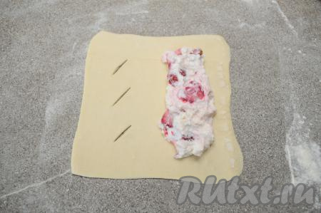 Ближе к правому краю, отступив от краёв 1,5-2 сантиметра, равномерно выложить 1 столовую ложку начинки из творога и клубники.