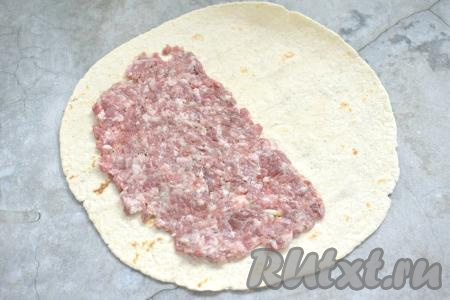 Выкладываем на стол лепёшку "Тортилья". Зрительно делим лепёшку на 2 половинки. На одну половинку лепёшки, отступив от края 1,5 сантиметра, равномерно выкладываем половину получившегося фарша.&nbsp;