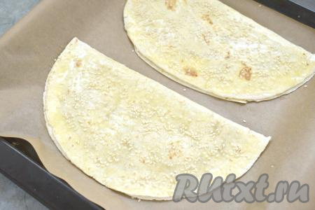 Аналогично формируем вторую тортилью с начинкой. Выкладываем тортильи с фаршем на противень, предварительно застеленный пергаментом. Поверхность тортильи смазываем яичным желтком и посыпаем кунжутом.