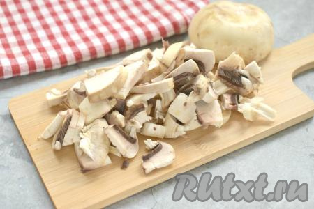 Промываем шампиньоны водой, нарезаем их на небольшие кубики. После того как картошка проварится 15 минут, добавляем в кастрюлю нарезанные грибы, даём закипеть, варим на небольшом огне 5 минут.