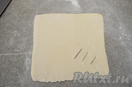 Каждый квадрат из теста раскатать в квадратный пласт со стороной примерно 16 сантиметров и толщиной 2 миллиметра. Ближе к одному из углов сделать три надреза на тесте.