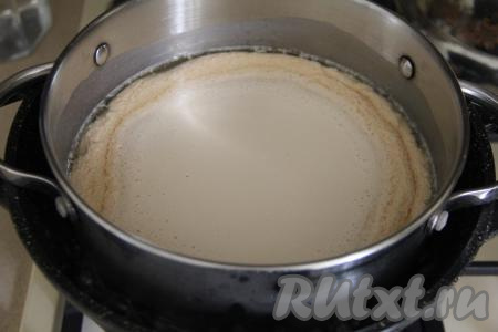 Поставить кастрюлю со смесью ряженки и сметаны на водяную баню. Для того чтобы сделать водяную баню, нужно поставить на огонь кастрюлю с водой, довести воду до кипения. Поверх кастрюли с водой поставить кастрюлю со смесью ряженки и сметаны. Кастрюля с ряженкой и сметаной не должна касаться дна кастрюли с водой, но при этом она должна быть в воде. Дать воде закипеть, а затем сразу уменьшить огонь. Варить смесь ряженки и сметаны на водяной бане с момента закипания 20 минут. Перемешивать не нужно. Ряженка начнёт створаживаться.