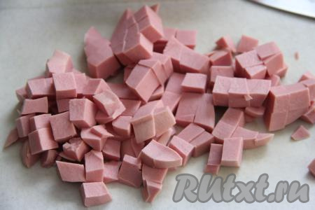 Дать воде закипеть, а затем на небольшом огне варить картошку с рисом 15 минут. В это время нарезать колбасу на средние кубики.