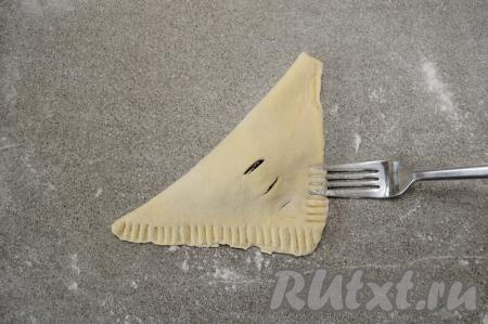 При помощи вилки скрепить два края конвертика. Для того чтобы вилка не приставала к слоёному тесту в процессе скрепления краёв, периодически окунайте кончик вилки в муку.