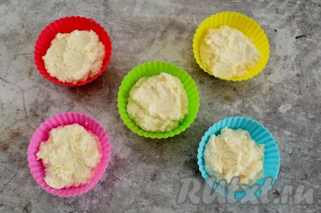 По прошествии 5 минут манка набухнет и тесто станет немного более вязким. Разложить его по силиконовым формочкам для выпечки кексов, заполняя не более, чем на 2/3 объёма. Можно вместо силиконовых формочек взять одну форму. Но помните, что для микроволновки не подходит металлическая посуда и посуда с блестящими вставками или рисунком. Если будете выпекать не в силиконовой форме, тогда перед выкладыванием теста смажьте форму маслом.