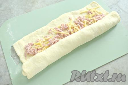 Сворачиваем тесто в неплотный рулет, начиная с широкой стороны теста.