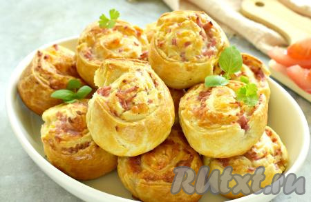 Достаём выпечку из духовки, накрываем полотенцем и даём немного остыть, а затем мягкие, вкусные, ароматные рулетики с аппетитной начинкой из колбасы и сыра подаём к столу. Такие рулетики из слоёного теста очень нравятся детям.