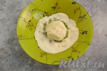 На тарелку насыпать 2 столовых ложки манки. Зрительно разделить творожное тесто на 4 равных части. Влажными руками из каждой части теста сформировать круглый сырник, обвалять его со всех сторон в манке.