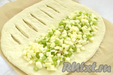 На сторону пласта теста без надрезов выкладываем начинку из ревеня и яблок, оставляя свободными по 2 сантиметра от каждого края.