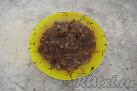 Первым делом изюм нужно выложить в глубокую тарелку, залить кипятком и оставить замачиваться на 5-10 минут, затем воду слить, переложить изюм на тканевое (или бумажное) полотенце и дать ему обсохнуть.