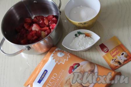 Подготовить продукты для приготовления пирога с замороженной клубникой из слоёного теста. Замороженную клубнику немного разморозить. Крупные ягоды нарезать на части. Прежде всего приготовим начинку для слоёного пирога, для этого нужно подготовленную клубнику переложить в кастрюлю с толстым дном.