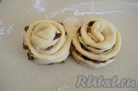 Взять сначала один разрезанный конец рулета и свернуть его в улитку так, чтобы разрез с изюмом был наружу. Аналогично свернуть второй конец рулета в улитку.