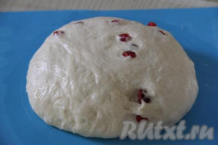 Вмешать вишню в тесто. Выложить тесто на поверхность, припылённую мукой, и обмять.