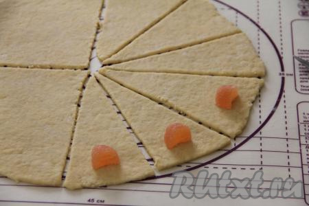 Мармелад разрезать на 2 части. Выложить по кусочку мармелада на край каждого сегмента, немного отступив от края теста, как на фото.&nbsp;