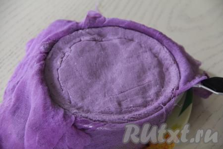 Поверх массы, накрытой марлей, выложить тарелку, на неё поставить гнёт (например, небольшую банку с водой). Убрать всю конструкцию (творожную пасху в сите, миску и гнёт) в холодильник на сутки. Затем аккуратно убрать тарелку с гнётом, развернуть края марли.