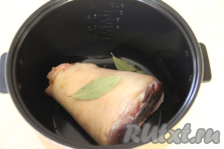 В чашу мультиварки&nbsp;Редмонд выложить свиную рульку, горошины перца и лавровые листья.