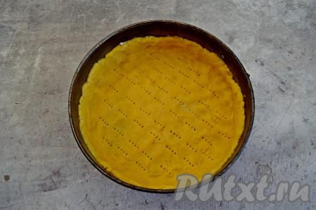 Дно и бока разъёмной формы (я взяла форму диаметром 24 сантиметра) смазать небольшим кусочком сливочного масла. Распределить тесто по дну формы, формируя невысокий бортик. Тесто наколоть вилкой.