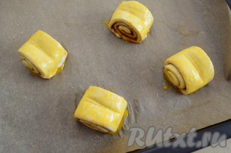 Яйцо в небольшой ёмкости взбить вилкой, а затем яичной смесью смазать каждую булочку с трёх сторон. 