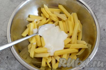 После того как голени пропитаются сметаной (как минимум, в течение 30 минут), можно заняться картофелем. Картошку нужно очистить, вымыть, затем нарезать на средние брусочки (или дольки). Посолить картофель, добавить к нему 2 столовых ложки сметаны.