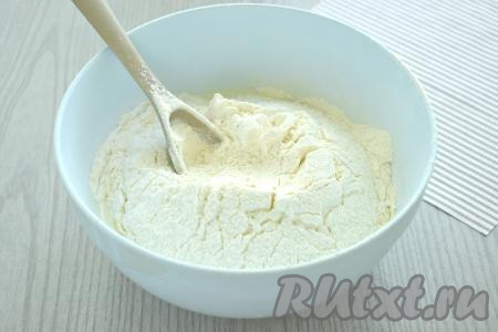 В получившуюся смесь просеиваем половину пшеничной муки вместе с разрыхлителем, перемешиваем ложкой.