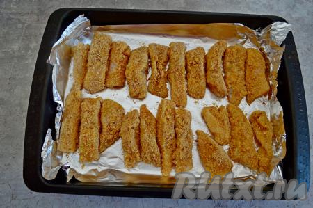 Противень застелить фольгой. Выложить на фольгу подготовленные рыбные палочки в кляре.