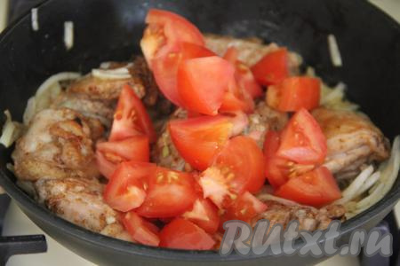 Помидоры вымыть, по желанию, снять с них кожуру, нарезать на средние кусочки и добавить в сковороду к курице, перемешать.