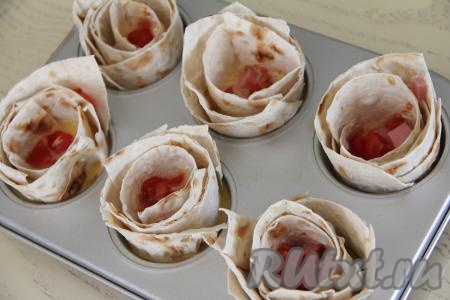 Разложить по формочкам поверх яичной массы нарезанные помидоры и колбасу.