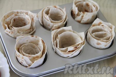 Формы для кексов смазать растительным маслом. В каждую формочку выложить рулетик из лаваша в виде розочки (я выкладывала в 6 формочек).