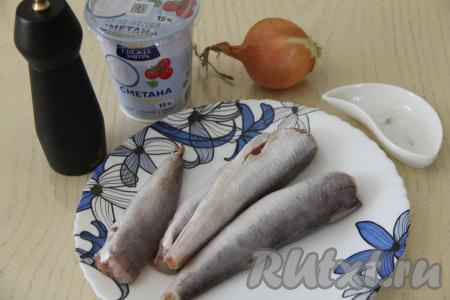 Подготовить продукты для приготовления хека в сметане с луком на сковороде. Хека разморозить полностью, отрезать плавники, если они есть, удалить из брюшек чёрную плёнку. Поскоблить поверхность рыбы ножом, счищаю чешую. Затем хека промыть водой. Лук почистить.&nbsp;